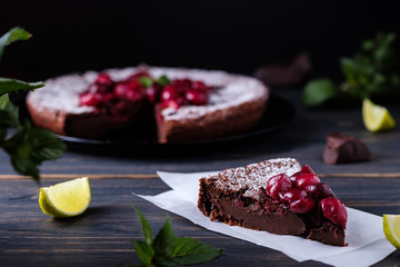 A slice of chocolate clafouti with a cherry on a wooden table. French delicious dessert. Fresh and beautiful cake.