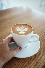Female hand holds a cup of cappuccino