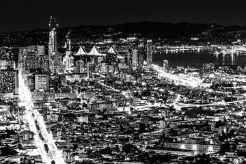 Black and white night pnoramic view of San Francisco downtown with skyscrapers and Okeland Bridge