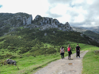 Fototapeta premium Three people walking on a dirt path in Asturias, Spain