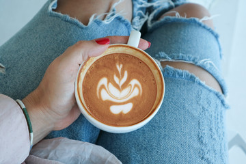 Fototapeta premium Female hand holds a cup of cappuccino