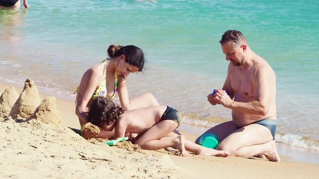 4K Happy family. Father playing sand with Cute Smiling little boy child and daughter on white sand beach on nature outdoor, Family travel, summer beach vacation with children concept.
