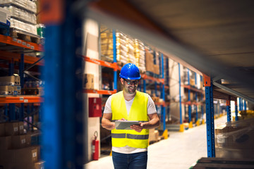Warehouse worker checking inventory in large warehouse distribution center.