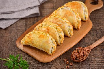 Meat roasted empanas on wooden background