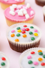 Colorful cupcakes on a pink background.