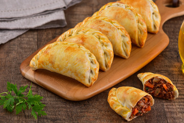 Meat roasted empanas on wooden background