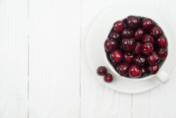 A lot of fresh sweet cherry fruit berries with water drops, close up in tea cup on white background. Close up of pile of ripe cherries. Large collection of fresh red cherries. Ripe cherries texture