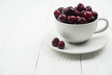A lot of fresh sweet cherry fruit berries with water drops, close up in tea cup on white background. Close up of pile of ripe cherries. Large collection of fresh red cherries. Ripe cherries texture