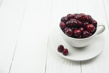 A lot of fresh sweet cherry fruit berries with water drops, close up in tea cup on white background. Close up of pile of ripe cherries. Large collection of fresh red cherries. Ripe cherries texture