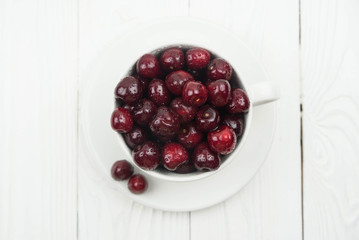 A lot of fresh sweet cherry fruit berries with water drops, close up in tea cup on white background. Close up of pile of ripe cherries. Large collection of fresh red cherries. Ripe cherries texture