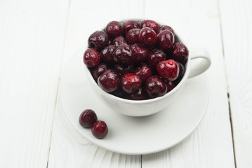 A lot of fresh sweet cherry fruit berries with water drops, close up in tea cup on white background. Close up of pile of ripe cherries. Large collection of fresh red cherries. Ripe cherries texture