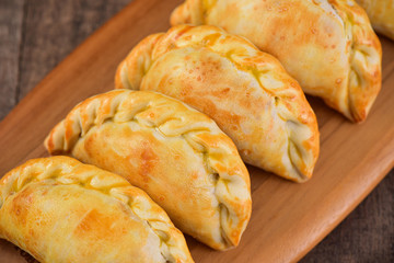 Meat roasted empanas on wooden background