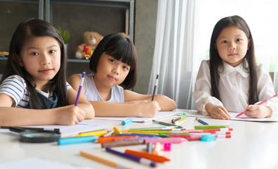 group of asian child little drawing with colourful pencils crayons in classroom.