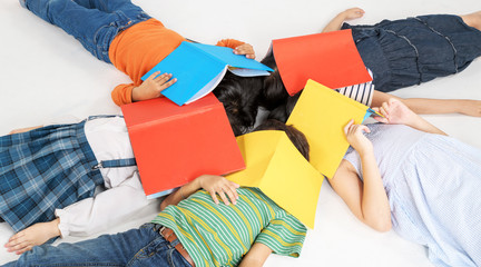 Kids reading book laying on the white floor ,head to head, in a circle group, preschool library,Kindergarten school education concept