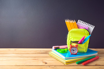 Back to school background with small bag backpack and school supplies on wooden table.