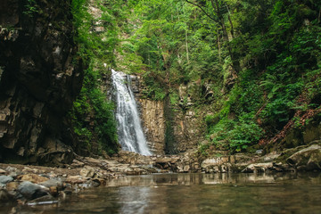 Fototapeta na wymiar Waterfall with a lake among rocks and forest