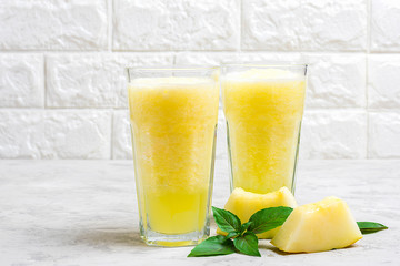 Melon lemonade, smoothie with ice and basil in a glass on the gray table. Summer refreshing and detox drink Rustic style Top view