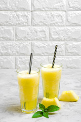 Fototapeta premium Melon lemonade, smoothie with ice and basil in a glass on the gray table. Summer refreshing and detox drink Rustic style Top view