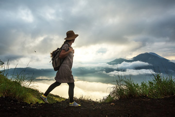 Fototapeta premium Woman enjoying sunrise from a top of mountain Batur, Bali, Indonesia.