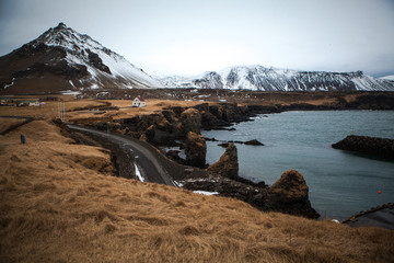 White house on the field in Iceland, grey road and ocean