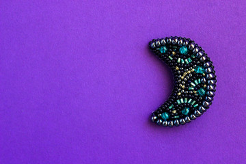 embroidered bead brooch in the form of the moon on a violet background