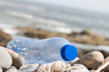 Close up of clear plastic bottle on a pebble beach