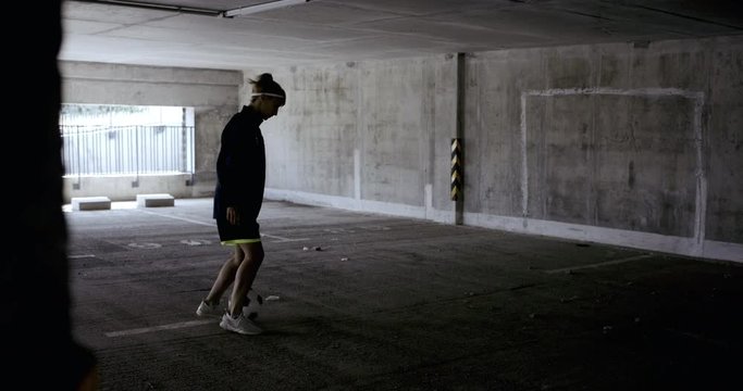 HANDHELD Teenager girl soccer player practicing kicks and moves inside empty covered parking garage. 4K UHD 60 FPS RAW graded footage