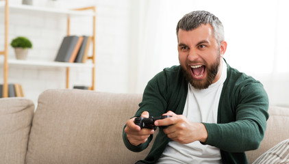 Middle-aged man playing video games at home