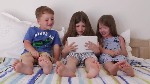 happy smiling children play games on the tablet, watch cartoons, laugh
