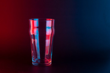 Beer glass on a black background with red and blue light 