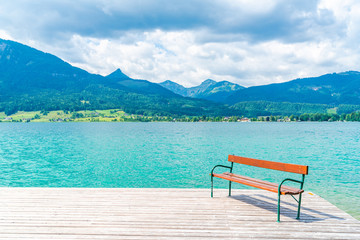 Naklejka na ściany i meble A bench on wooden deck by Lake St. Wolfgang in the Salzkammergut resort region, Austria