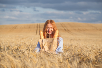 Redhead woman with bakery products in ripe wheat field.