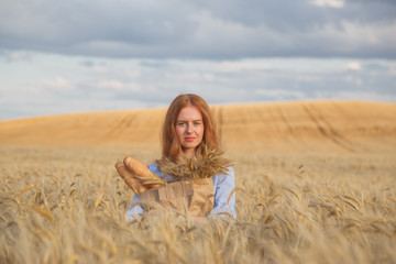 Naklejka na ściany i meble Redhead woman with bakery products in ripe wheat field.