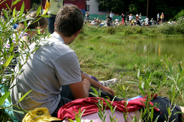 młody chłopak siedzi na trawie, na biwaku - obrazy, fototapety, plakaty