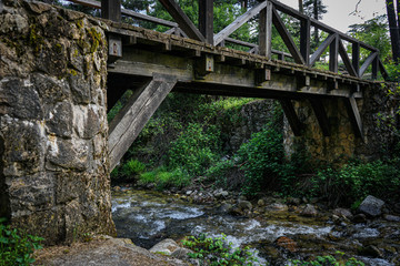 Fototapeta na wymiar Wooden and stone bridge over the river in the woods