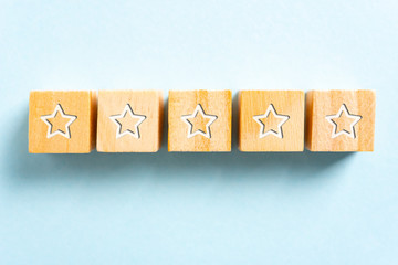 White five stars illustrated on wood blocks toy and blue background. Branding, reputation and feedback concept.