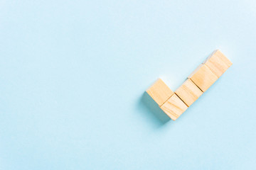 Check mark made with wooden block toys on blue background with blank space to the left. Tick symbol. Opinion, agree concept concept concept