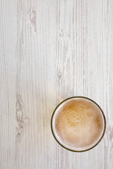 Glass of light beer on a white wooden background, top view. Overhead, from above. Copy space.