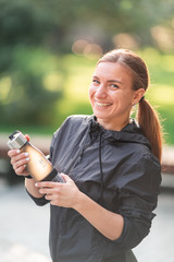 Happy sportive woman drinking water during fitness exercises