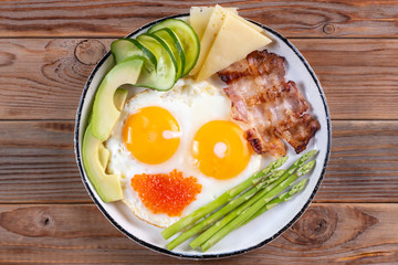 Top view of ketogenic diet breakfast on the white plate on wooden background.