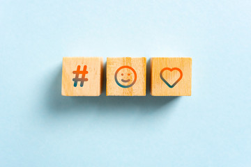 Social media icons. Hashtag, happy smiling face and heart icons on wood blocks toys and blue background. Rating and viral concept.