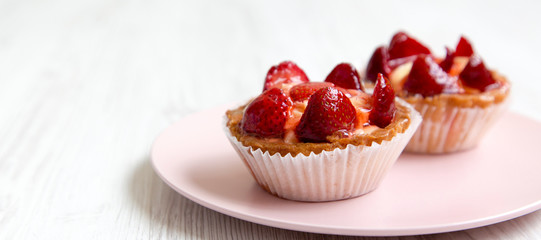 Strawberry vanilla cream cheese tarts on a pink plate, side view. Copy space.