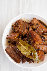 Homemade Filipino Adobo Pork in a white bowl, overhead view. Flat lay, from above, top view. Close-up.