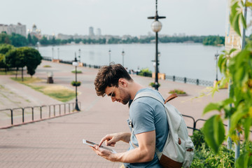 handsome man in glasses with backpack using digital tablet