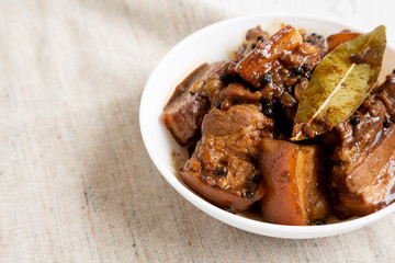 Homemade Filipino Adobo Pork in a white abowl, side view. Copy space.