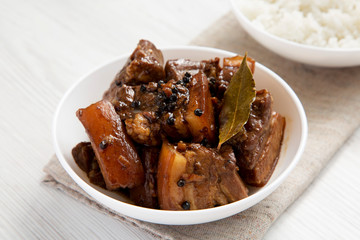 Homemade Filipino Adobo Pork with rice on a white wooden surface, low angle view. Close-up.