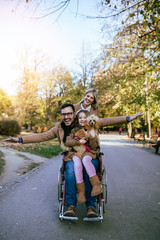 Disabled father in wheelchair enjoying with his daughter and wife outdoors in park.
