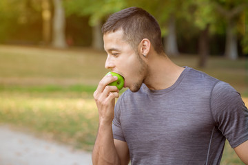 Young man eating apple in a park copyspace copy space runner sports training