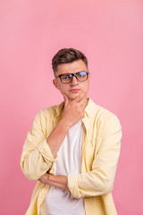 Young man thinking about things. Cropped shot of thoughtful young man standing near pink background