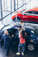 Happy family buying a new car at the car showroom.